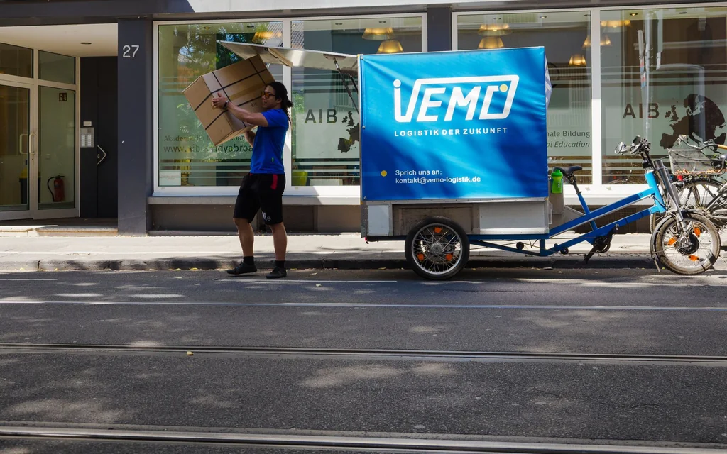 VEMO-Fahrer mit Lastenrad-Anhänger bei der Zustellung